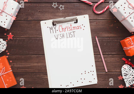 Creative sullo sfondo di Natale. Wishlist con copia spazio per il testo su sfondo di legno con doni Foto Stock