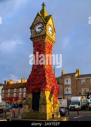 La città orologio nella Piazza del Mercato di Thirsk North Yorkshire Regno Unito decorate con papaveri di maglia per il giorno del ricordo per i morti di guerra Foto Stock