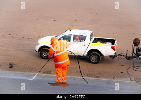 Redcar e Cleveland Consiglio lavoratore usando alta pressione di eiezione di acqua per pulire le fasi di fornire un accesso sicuro a Redcar beach Foto Stock