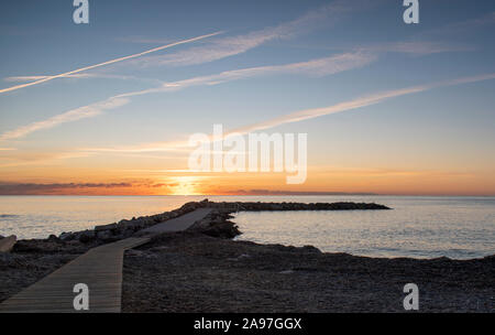 Sunrise in Cala Bona Maiorca con il sole che appare all'orizzonte. Foto Stock