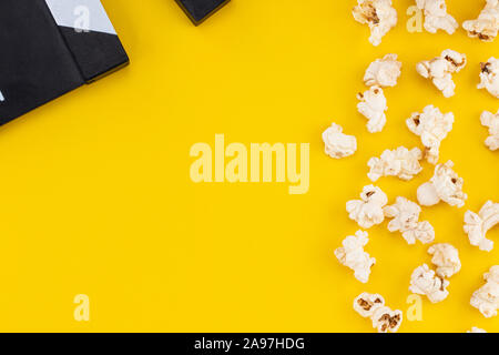 Popcorn e clapperboard su sfondo colorato. Vista dall'alto. Foto Stock