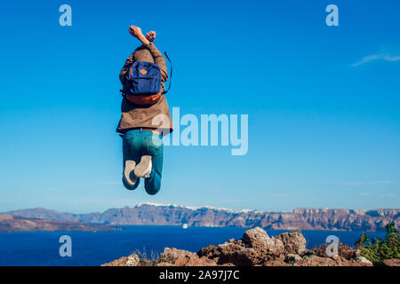 L'uomo traveler jumping sentirsi liberi e felici di Santorini isola in autunno. Tourist ammirando vista sulla Caldera paesaggio Foto Stock