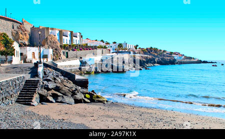 Strada sulla spiaggia con case bianche su un lato nel sud delle isole Canarie di Tenerife in una giornata di sole Foto Stock