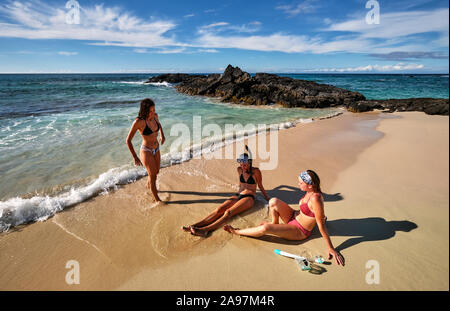 Tre amici godendo le onde e la sabbia sulla spiaggia Makalawena, Hawaii Foto Stock