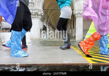 La gente che camminava sul sentiero sopraelevato passerella durante l'imponente alluvione in Venezia in Italia Foto Stock