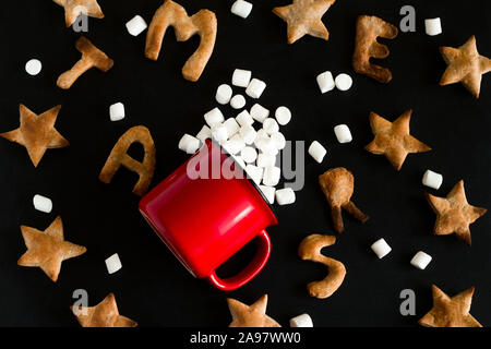 Vista superiore piatta modello di laici di biscotti allo zenzero conformata come stelle e lettere buon Natale e red mug con marshmallow pasticcio su sfondo nero Foto Stock