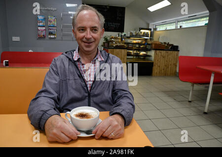 L'uomo godendo un cappuccino al caffè a Eastleigh Lakeside Steam Railway, Lakeside Country Park, Eastleigh, Southampton, Hampshire, Regno Unito Foto Stock