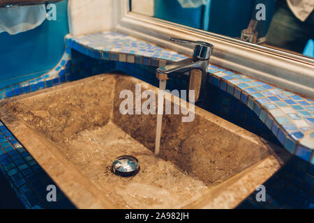 Interni dal design moderno nel ristorante pubblico wc. Dissipatore di vintage, tocca con specchio e piastrelle blu Foto Stock