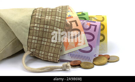 Le banconote e le monete in un sacchetto davanti a uno sfondo bianco Foto Stock