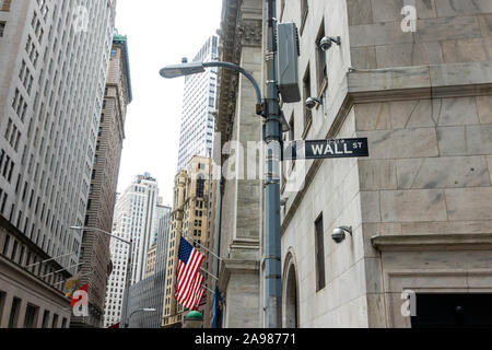 Wall St strada segno con noi bandiera sul New York Stock Exchange e grattacieli in background Foto Stock