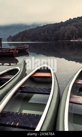 Canoe sul lungolago nella nebbia fredda mattina autunnale a Ribcev Laz, Slovenia Foto Stock