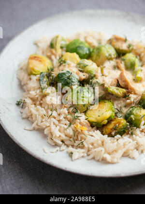 Arrosto di cavolini di Bruxelles con chickun vegana e una salsa Alfredo sul riso Foto Stock