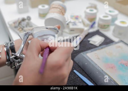 Odontotecnico lavora su intonaco modello di pietra con ponte di zirconio e di applicazione della ceramica Foto Stock