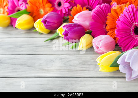 Gerbera e tulipani contro lo sfondo di legno Foto Stock