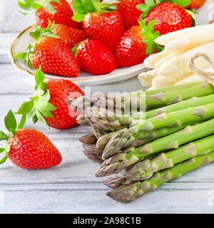 Gli asparagi e le fragole contro lo sfondo di legno Foto Stock