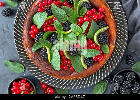 Cheesecake al forno con frutti e foglie di menta. Vista da sopra con copia spazio. Foto Stock