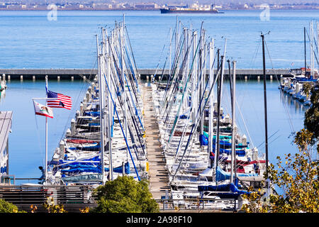 Novembre 2, 2019 San Francisco / CA / STATI UNITI D'AMERICA - imbarcazioni ormeggiate presso il South Beach porto; la bandiera americana e la California Repubblica bandiera sventolare nel vento Foto Stock