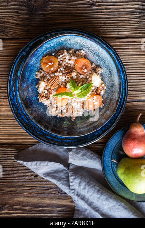 Vegano sana insalata di grano saraceno con albicocche secche, pere e noci pecan su sfondo di legno Foto Stock