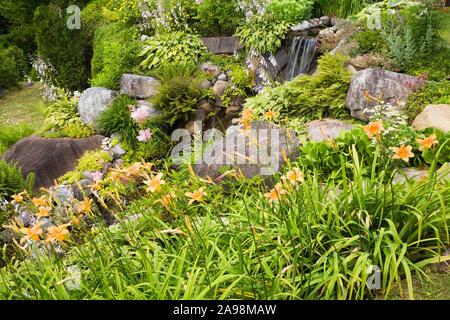 Cascata e rock refilato stream delimitata da rosa Astilbe, Hosta - Plaintain Lily, arancione Hemerocallis - Daylilies, Lamium - Deadnettle Foto Stock