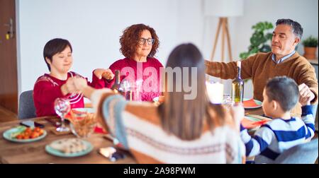 Bella famiglia sorridendo felice e fiducioso. Pregando insieme tenendo le mani per celebrare il Natale a casa Foto Stock