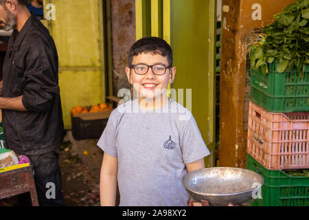 Ragazzo locale funzionante a un cavalletto di vegetali nella zona Souk, Tripoli o Trablus, Libano Foto Stock