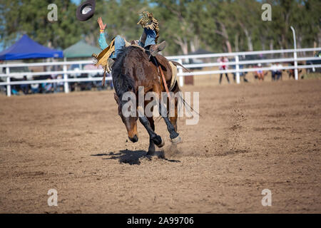 Cowboy è caduta la sua cavalcata su strappi cavallo in bareback bronc evento in un paese rodeo e perde il suo cappello. Foto Stock