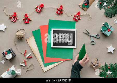 Rifiuti Zero il Natale, piatto di laici che, vista dall'alto sulla carta craft sfondo con bambola tessili garland, avvolto doni, lavagna con il testo 'Buon Natale' su Foto Stock