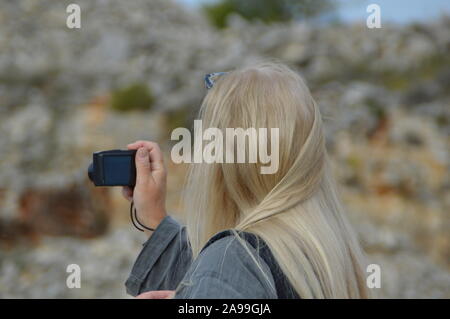 Vista posteriore del ritratto di donna bionda tenendo la foto in natura Foto Stock