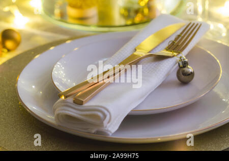 Tavola di Natale impostazione con le piastre bianche e oro posate. Elegante cena di gala con uno sfondo con spazio di copia. Xmas vasellame sfondo. Foto Stock