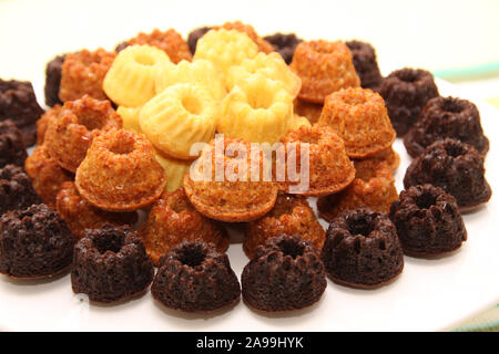 Mini guglhupf impilati sulla piastra bianca mini bundt cake in marrone, jellow, cioccolato Foto Stock