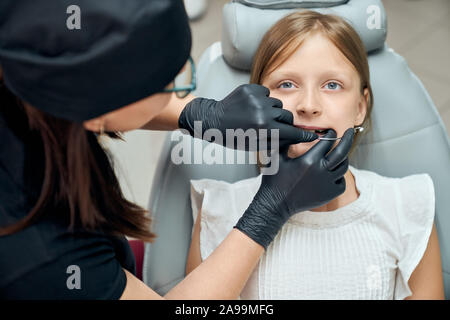 Giovane e bella ragazza visita clinica dentale per il trattamento e l'allineamento dei denti. Dentista femmina di ispezionare la bocca e cercando le bretelle. Concetto moderno di stomatologia. Foto Stock