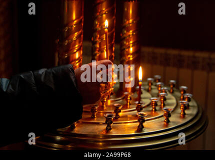 Donna illuminazione a mano candele in una chiesa Foto Stock