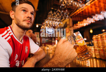 Party entusiasta gli appassionati di arsenale che guardano il calcio con Ganzberg Beer in il pub Foto Stock