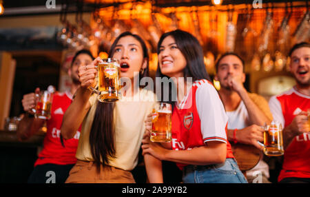 Party entusiasta gli appassionati di arsenale che guardano il calcio con Ganzberg Beer in il pub Foto Stock