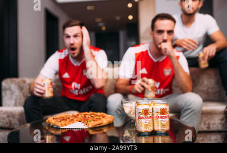 Fai festa con gli amici o con gli appassionati di arsenale guardando il calcio tv e bere birra Ganzberg celebrando la vittoria a casa Foto Stock