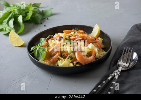 Pasta reginelle spaghetti ai frutti di mare, gamberi, cozze piastra nero su grigio tavolo di pietra, vicino. Piatto tradizionale nel ristorante italiano a Milano, R Foto Stock