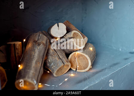 I log di un albero sono collocati sulla parete. Imitazione di un caminetto nella parete, le luci di una ghirlanda di fiori con i registri Foto Stock