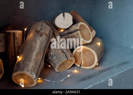 I log di un albero sono collocati sulla parete. Imitazione di un caminetto nella parete, le luci di una ghirlanda di fiori con i registri Foto Stock