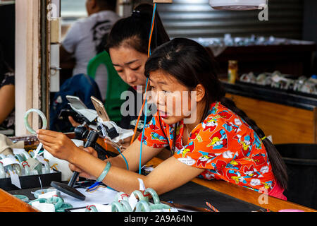 Una femmina di concessionari esaminando Jade al Mercato della Giada, Mandalay Myanmar. Foto Stock