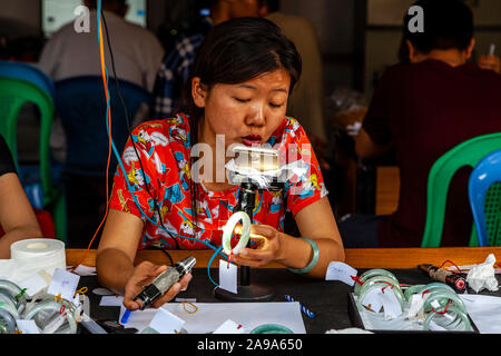 Un concessionario femmina esaminando Jade al Mercato della Giada, Mandalay Myanmar. Foto Stock