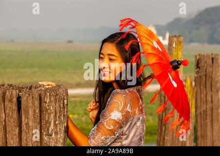 Una giovane donna con un ombrellone in piedi sulla U Bein Bridge, Amarapura, Mandalay Myanmar. Foto Stock