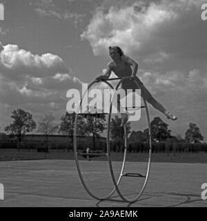 Una giovane donna che esercitano con il suo gymwheel su un terreno sportivo, Germania 1930s. Foto Stock