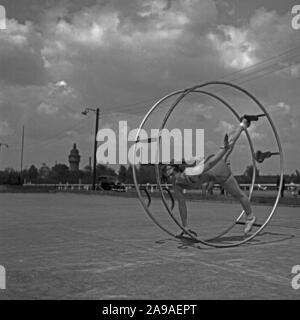 Una giovane donna che esercitano con il suo gymwheel su un terreno sportivo, Germania 1930s. Foto Stock