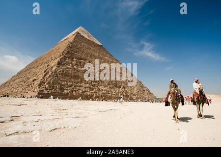 Giza, Cairo, Egitto, 2 Maggio 2008: la piramide di Khafre torreggia su turisti e due uomini a cavallo di cammelli sull'altopiano di Giza vicino al Cairo, Egitto. Foto Stock