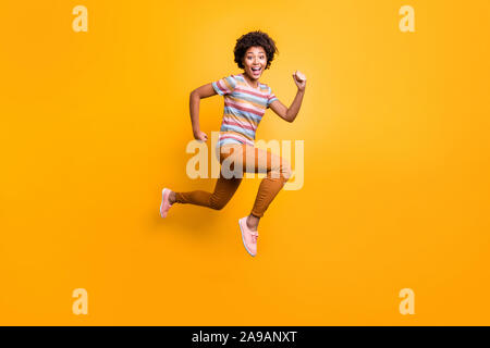 Corpo pieno della foto del profilo di salti ad alta pelle scura ondulata lady gara di velocità in esecuzione campione casuale indossare vestiti estivi isolato colore giallo brillante Foto Stock