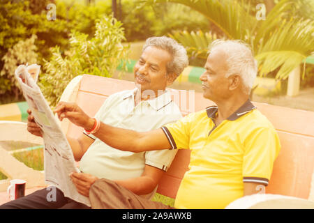Due lieti alti uomini lettura quotidiano a park outdoor - amici anziani godendo di mattina news - Nozione di felice di uomini anziani lifestyle. Foto Stock