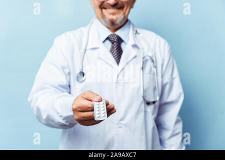 Medico dando pillole medicinali. su sfondo blu. Il concetto di medicina, farmacologia, healthcare. Foto Stock