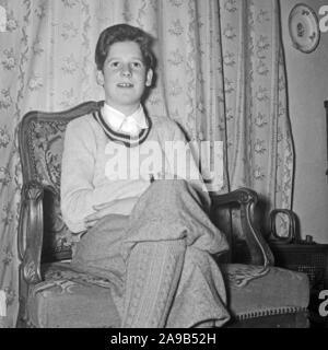 Un ragazzo che indossa kniccurbockers seduto in una sedia al soggiorno, Germania 1954 Foto Stock