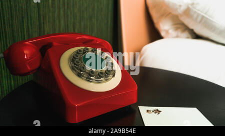 Close-up sul rosso, vintage Ricerca telefono con pulsanti sul comodino con il blocco note e matita Foto Stock