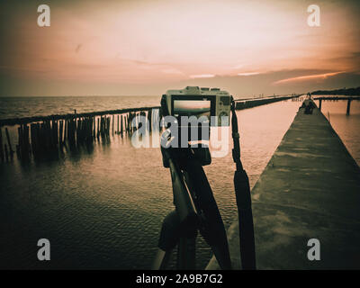 La fotocamera su un treppiede . a scattare foto dei momenti belli durante il tramonto ,sunrise.Silhouette della fotocamera su treppiede sullo sfondo di paesaggi marini. ri Foto Stock